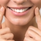Gros plan sur la bouche d'une femme souriante montrant ses dents blanches, avec ses doigts pointant vers ses joues.